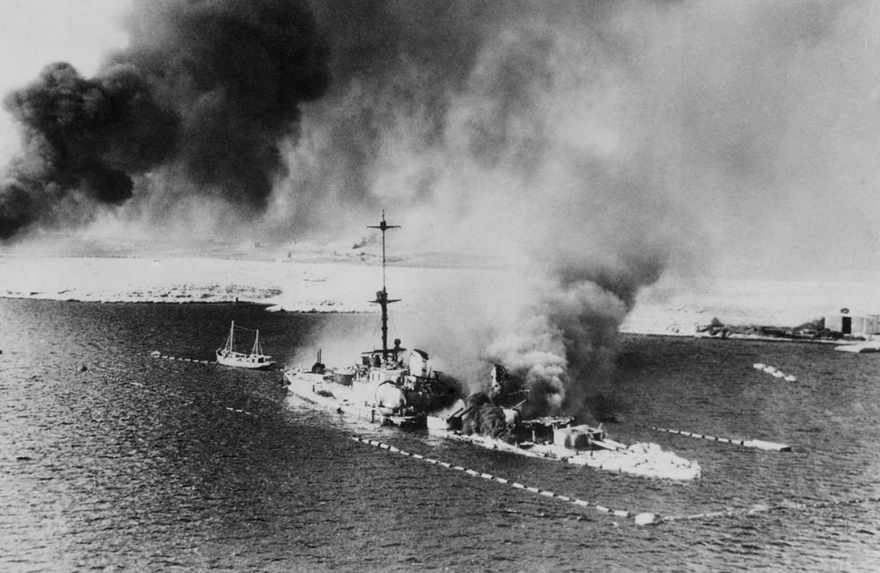 На этой фотографии, сделанной с британского военного самолета во время штурма Тобрука, изображен итальянский крейсер San Giorgio, горящий на миделе, в порту Тобрука 18 февраля 1941 года. Корабль затоплен, его палубы разбиты.