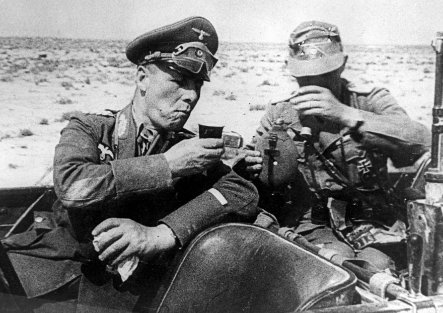 Генерал-фельдмаршал Эрвин Роммель, командующий немецкой Африкой Корпс, выпивает из чашки неизвестного немецкого офицера, когда они садятся в машину во время осмотра немецких войск, направленных в помощь итальянской армии в Ливии в 1941 году.