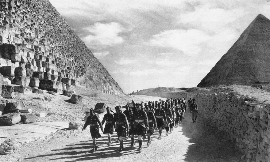 9 декабря 1940 года шествие пехотного полка британской армии Камерон-Хайлендерс и индийские войска проходят мимо Великой пирамиды в пустыне Северной Африки.
