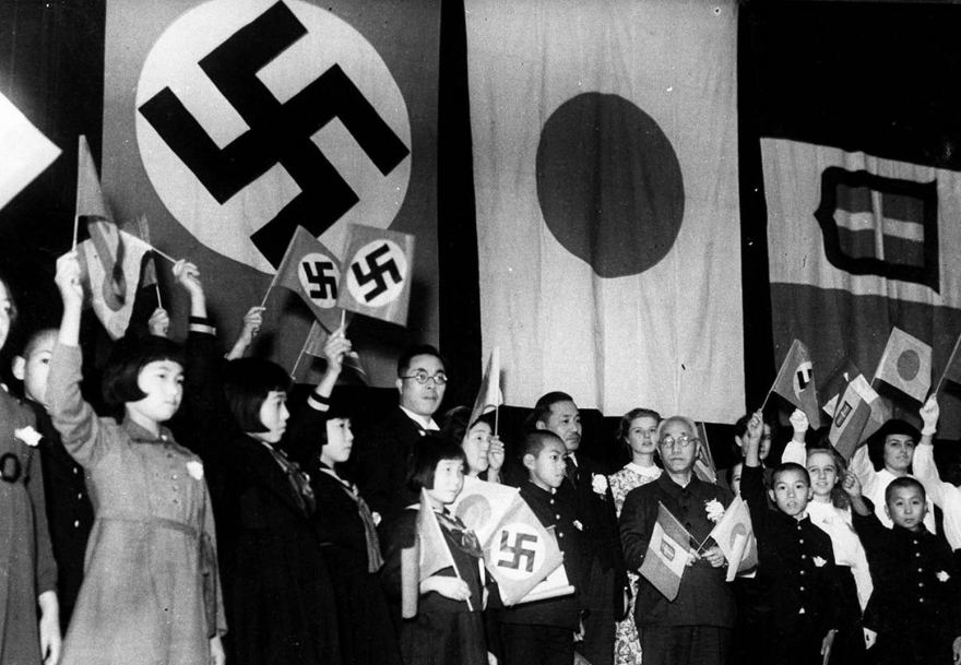 Дети из Японии, Германии и Италии встречаются в Токио, чтобы отпраздновать подписание Трехстороннего альянса между тремя народами 17 декабря 1940 года. Министр образования Японии Кунихико Хашида (в центре держат скрещенные флаги) и мэр Токио Окубо так же был среди присутствующих.