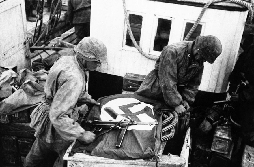 Чтобы предупредить свои военно-воздушные силы о своем присутствии, солдаты распространили свастику по лодкам, которые использовались войсками СС для пересечения Коринфского залива, Греция, 23 мая 1941 года.
